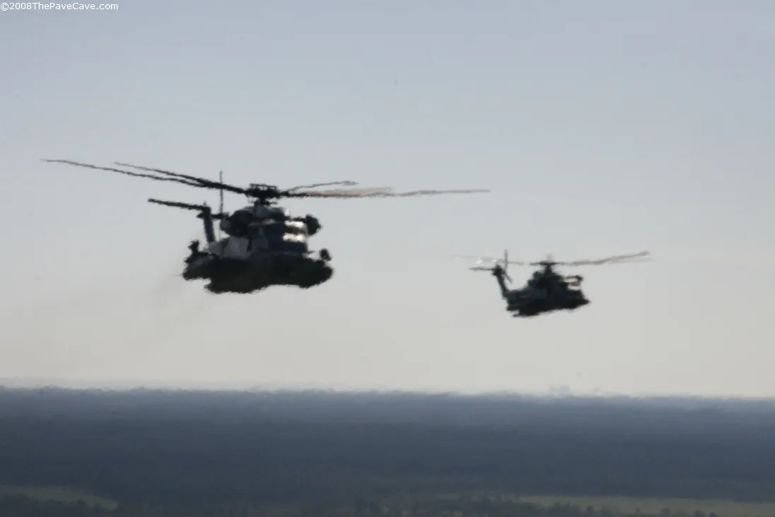 Two MH-53 PAVE LOWs flying in formation low over the treeline